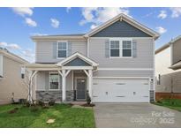 Charming two-story home with gray siding, stone accents, well-manicured lawn, and a two-car garage at 2592 Blue Sky Meadows Dr, Monroe, NC 28110