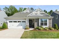 Charming home featuring a gray roof, stone accents, manicured lawn and an attached two car garage at 2658 Manor Stone Way, Indian Trail, NC 28079