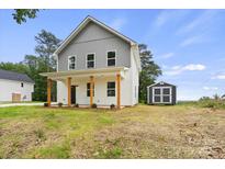 Charming two-story home featuring white siding, gray accents, a covered porch, and a storage shed in the backyard at 27 Mickley Ave, Bessemer City, NC 28016