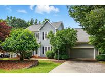 Charming two-story home featuring gray siding, black shutters, mature trees, and an attached two-car garage at 2725 Cotton Planter Ln, Charlotte, NC 28270