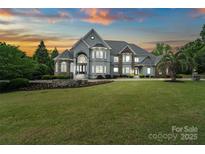 Stunning two-story home with manicured lawn and lush landscaping against a colorful twilight sky at 2971 Kaneland Ct, Rock Hill, SC 29732