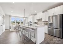 Bright kitchen with stainless steel appliances, marble countertops, an island, and gray chairs at 3114 Stelfox St, Charlotte, NC 28262