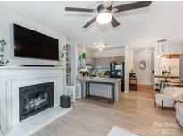 Cozy living room featuring a fireplace, TV, ceiling fan and an open layout to a modern kitchen with an island at 3308 Selwyn Farms Ln # 2, Charlotte, NC 28209