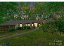 Evening view of wood and stone home, surrounded by trees and mature landscaping at 4417 Walter Nelson Rd, Mint Hill, NC 28227