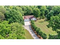 A charming single-Gathering home with an attached two-car garage sits nestled among lush trees on a sprawling green lawn at 6992 Sherrills Ford Rd, Sherrills Ford, NC 28673