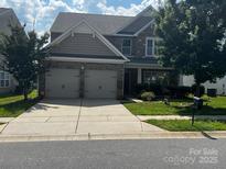 Charming two-story home featuring a two-car garage and stone and siding details, complemented by a well-manicured lawn at 10211 Snowbell Ct, Charlotte, NC 28215