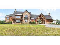 Stunning stone and wood exterior home with a porte-cochère and meticulously manicured lawn at 1822 Irby Rd, Monroe, NC 28112