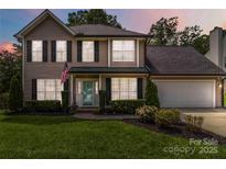 Two-story home featuring black shutters, an American flag, a well-manicured lawn, and a two-car garage at 204 Pebble Creek Xing, Fort Mill, SC 29715