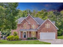 Beautiful two-story brick home with manicured lawn and mature trees under a dramatic sky at 3741 Tea Olive Rd, Gastonia, NC 28056