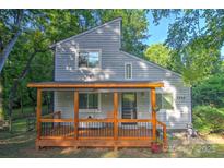 Charming two-story home with a covered wooden porch surrounded by lush trees at 5995 Tall Tree Ln, Harrisburg, NC 28075