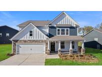 Charming two-story home boasts stone accents, a covered porch, and an attached two-car garage at 7137 Butternut Oak Ter, Huntersville, NC 28078