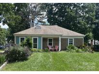 Charming brick home featuring a well-maintained lawn, colorful landscaping, and a cozy porch with two pink chairs at 7607 Swedish Ivy Ln, Charlotte, NC 28227