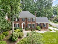 Stunning brick home featuring mature trees, lush landscaping, a chimney, and a classic facade at 8700 Thornbury Ln, Huntersville, NC 28078