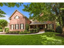 Beautiful brick home featuring lush landscaping, black shutters, and a covered porch, offering classic curb appeal at 9021 Unbridle Ln, Waxhaw, NC 28173