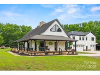 Charming white farmhouse with a sprawling front porch and black accents, surrounded by a lush green lawn at 930 Hawley Rd, McConnells, SC 29726