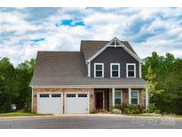 Charming two-story home featuring a stone facade, gray siding, two-car garage, and landscaped front yard at 10100 Jack Nicklaus Dr, Lancaster, SC 29720