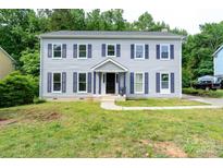Charming two-story home with gray siding and blue shutters surrounded by a luscious green lawn at 1013 Doby Springs Dr, Charlotte, NC 28262