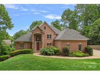 Charming red brick home featuring a manicured front yard and a vibrant red front door at 166 Pinnacle Shores Dr, Mooresville, NC 28117