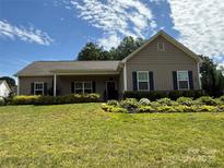 Charming one-story home featuring meticulously landscaped yard and a welcoming covered front porch at 190 Watering Trough Rd, Statesville, NC 28677