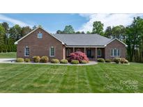 Charming brick home featuring a well-manicured lawn and mature landscaping at 2458 Genelia Dr, Claremont, NC 28610