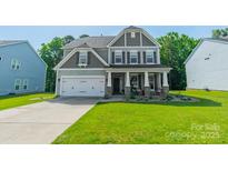 Charming two-story home with a manicured lawn, neutral siding, stone accents, and a welcoming front porch at 2714 Woodlands Creek Dr, Monroe, NC 28110