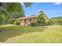 Charming brick home with a well-manicured lawn and mature trees, creating a peaceful curb appeal at 6300 Mount Pleasant S Rd, Concord, NC 28025