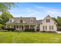 Charming home featuring a large front lawn and inviting front porch with classic architectural detailing at 6409 Barkley Farm Rd, Huntersville, NC 28078