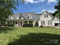 Charming home featuring a covered front porch, lush lawn, and mature landscaping at 6409 Barkley Farm Rd, Huntersville, NC 28078