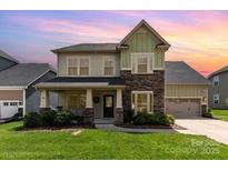 Charming two-story home with a combination of siding and stone exterior, lush lawn, and inviting front porch at 8829 Keller Ct, Huntersville, NC 28078