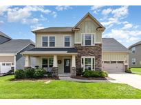 Charming two-story home with stone accents, a covered front porch, and well-manicured landscaping at 8829 Keller Ct, Huntersville, NC 28078