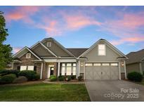 Charming, single-Gathering home featuring a stone facade, a two-car garage and manicured landscaping at dusk at 8830 Artesa Mill Ln, Charlotte, NC 28214
