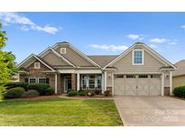 Charming single-Gathering home with stone accents, neutral siding, manicured lawn, and a two-car garage at 8830 Artesa Mill Ln, Charlotte, NC 28214