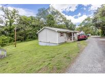 Quaint home featuring light siding, green lawn, and gravel driveway at 100 Lanier St, Mount Holly, NC 28120