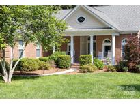 Charming brick home featuring a covered front porch with classic columns and beautifully manicured landscaping at 122 Waterford Dr, Mooresville, NC 28117