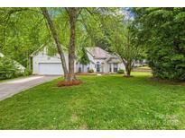 Charming home with a lush green lawn, mature trees, and a welcoming two-car garage at 125 Canopy Ct, Mooresville, NC 28115