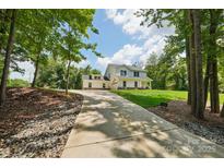 Charming two-story home featuring a long driveway, well-manicured lawn, and lush landscaping at 127 Wickersham Dr, Statesville, NC 28625