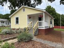 Charming yellow home featuring an inviting front porch with flower baskets at 1510 Stoker Ter, Albemarle, NC 28001