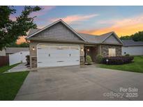 Charming home boasts a two-car garage, stone accents, manicured lawn, and inviting facade at dusk at 2021 Chantilly Ln, Salisbury, NC 28146