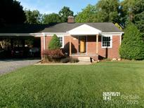 Charming brick home with a well-manicured lawn, carport, and inviting front porch at 2357 28Th Ne St, Hickory, NC 28601