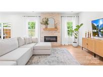 Bright living room features a stone fireplace, white sectional sofa, and lots of natural light at 3110 Streamside Dr, Davidson, NC 28036