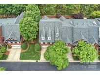 Aerial view of a red brick townhome with a gray shingle roof and mature trees at 3128 Ethereal Ln, Charlotte, NC 28226