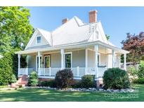 Charming home showcasing a inviting front porch, landscaped yard, and architectural details under a clear blue sky at 328 E Center Ave, Mooresville, NC 28115