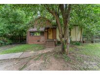 Charming brick and siding home with covered porch and mature trees in a secluded setting at 3924 Tillman Rd, Charlotte, NC 28208