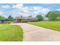 Charming brick home featuring a well-manicured lawn, long driveway, and mature trees providing shade at 405 W Ormand Ave, Bessemer City, NC 28016