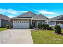 Charming single-story home with a two car garage and a well-manicured front yard under a blue sky at 4243 Merrivale Dr, Lancaster, SC 29720