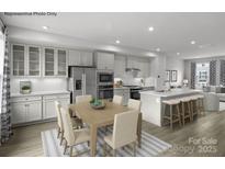 Open-concept kitchen features white cabinets, stainless steel appliances, and a spacious island with bar seating at 5030 Grain Orchard Rd # 3025C, Indian Trail, NC 28079