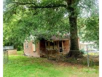 Exterior shot of a small weathered home surrounded by trees, with a chainlink fence at 711 East Dr, Cherryville, NC 28021