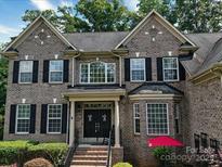 Charming brick two-story home featuring black shutters, arched windows and manicured landscaping at 9913 Hazelview Dr, Charlotte, NC 28277