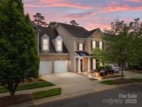 Charming brick townhome with a well-manicured lawn and attached two-car garage at dusk at 10206 Linksland Dr, Huntersville, NC 28078