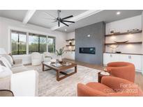 Bright living room featuring a modern fireplace, shelving, and a large window with scenic views at 111 Monbo Meadows Ln, Statesville, NC 28677